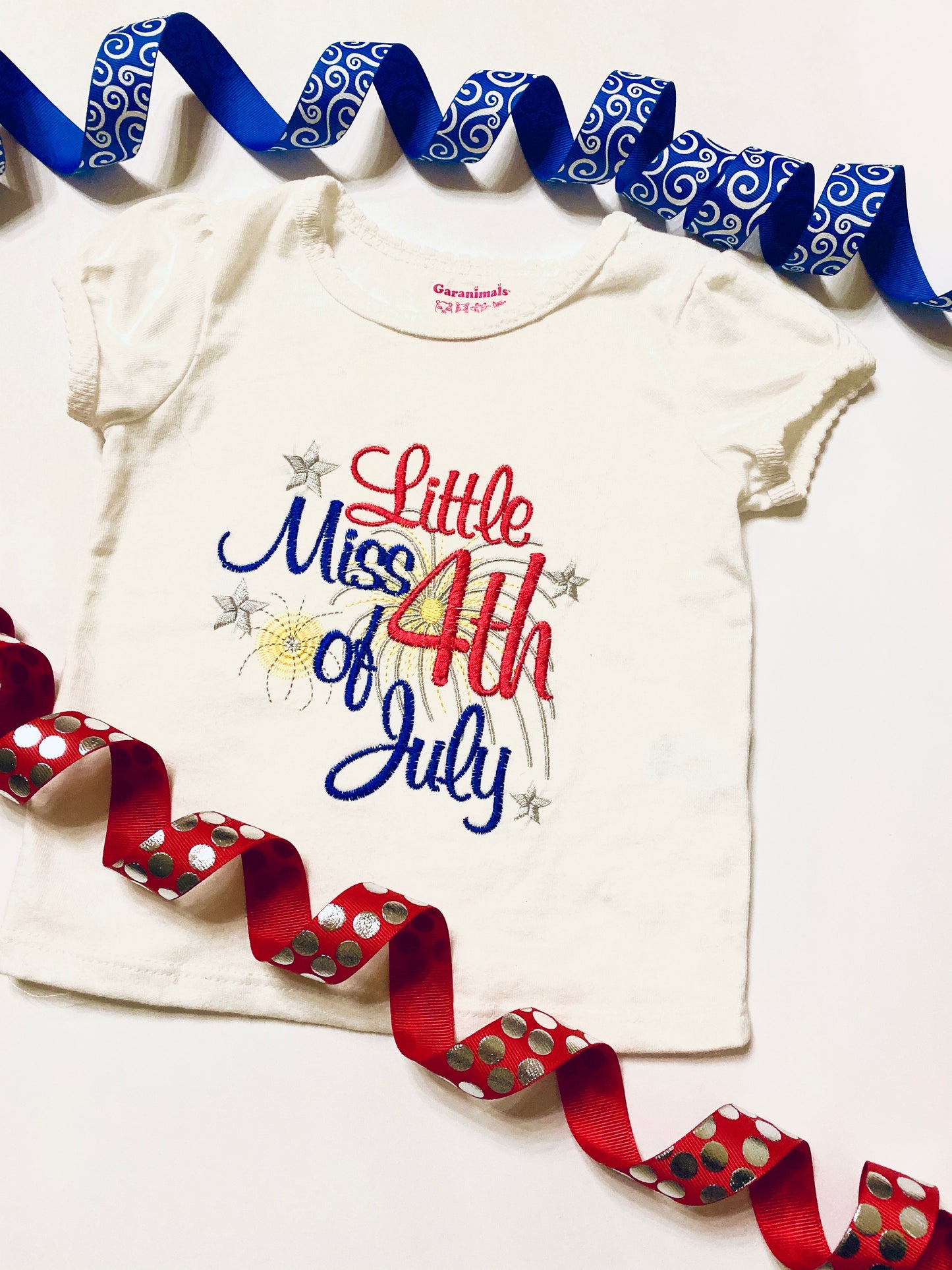 patriotic shirt stitched with red white blue gold and silver thread, reads Little Miss 4th of July Shirt is a white cotton.